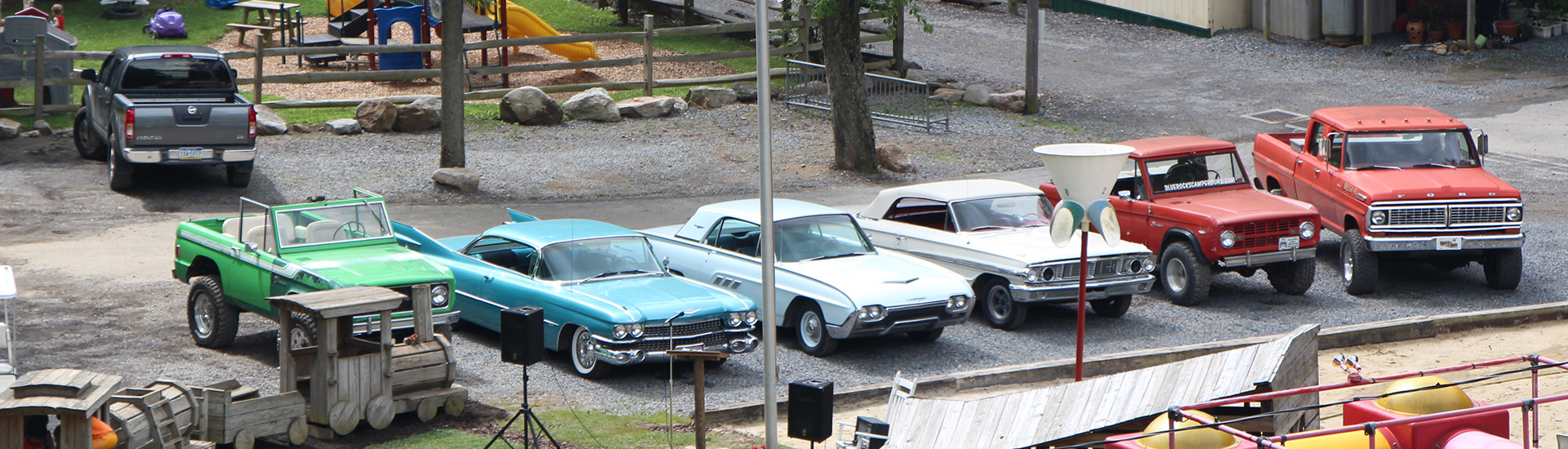 An array of classic cars parked by the playground.
